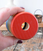 Mader Rainbow Kaleidoscope placed in an adult's hand with the viewing peep hole facing the camera. 