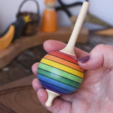 Mader Kreiselmanufaktur rainbow lolly spinning top in an adult's hand in the Babipur playroom.