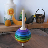Mader Kreiselmanufaktur rainbow lolly spinning top spinning in motion on a walnut spinning plate in the Babipur playroom.