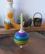 Mader Kreiselmanufaktur rainbow lolly spinning top spinning in motion on a walnut spinning plate in the Babipur playroom.