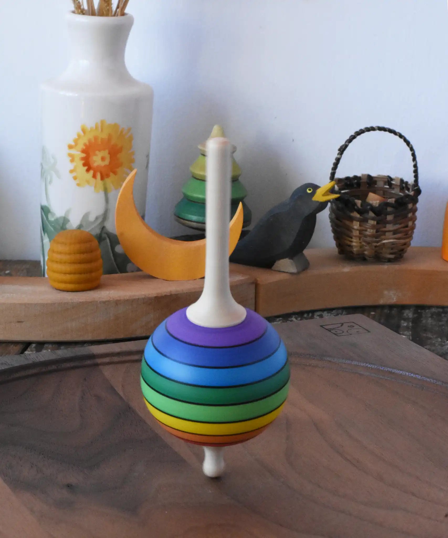 Mader Kreiselmanufaktur rainbow lolly spinning top spinning in motion on a walnut spinning plate in the Babipur playroom.
