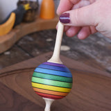 Mader Kreiselmanufaktur rainbow lolly spinning top being placed on a walnut wood spinning plate in the Babipur playroom.