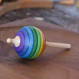 Mader Kreiselmanufaktur rainbow lolly spinning top placed on a walnut spinning plate in the Babipur playroom.