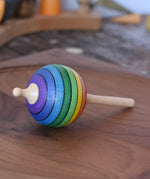 Mader Kreiselmanufaktur rainbow lolly spinning top placed on a walnut spinning plate in the Babipur playroom.