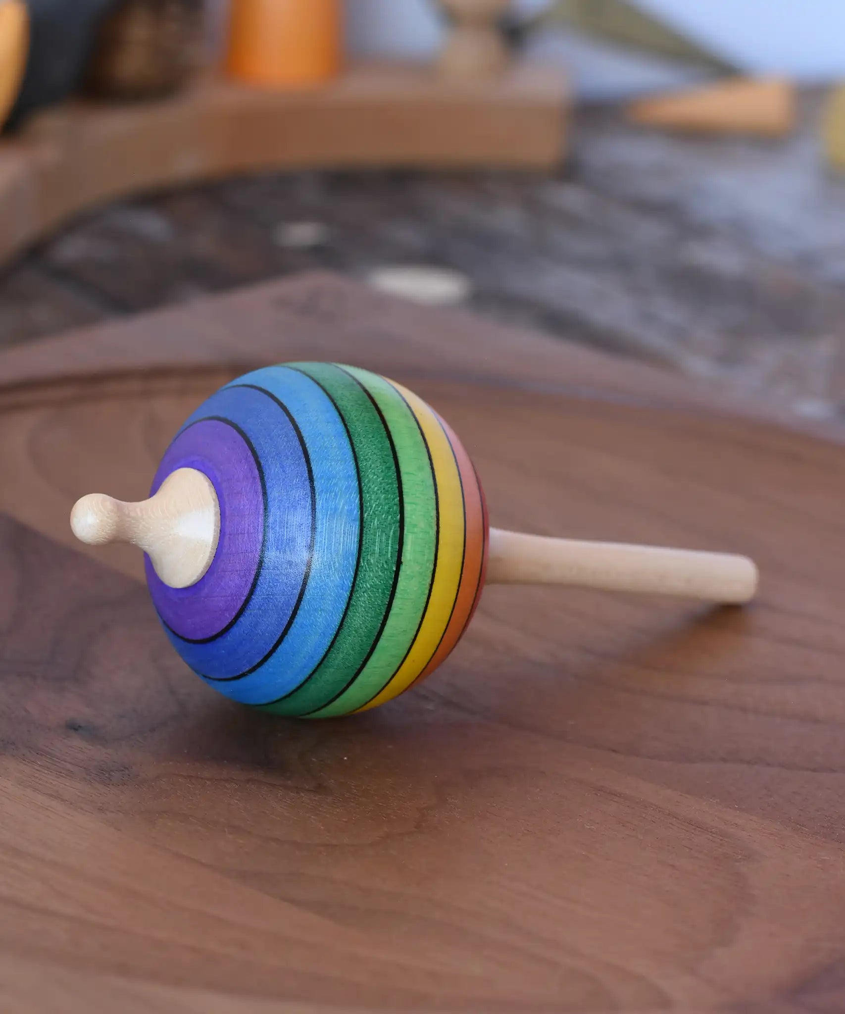 Mader Kreiselmanufaktur rainbow lolly spinning top placed on a walnut spinning plate in the Babipur playroom.
