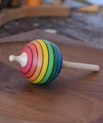 Mader Kreiselmanufaktur rainbow lolly spinning top placed on a walnut spinning plate in the Babipur playroom.