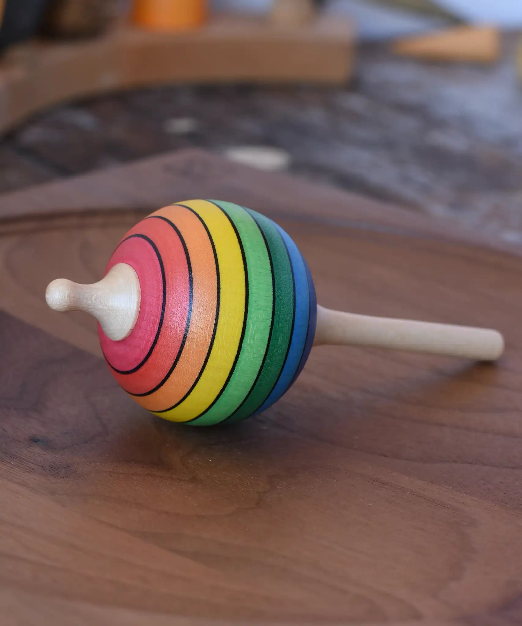 Mader Kreiselmanufaktur rainbow lolly spinning top placed on a walnut spinning plate in the Babipur playroom.