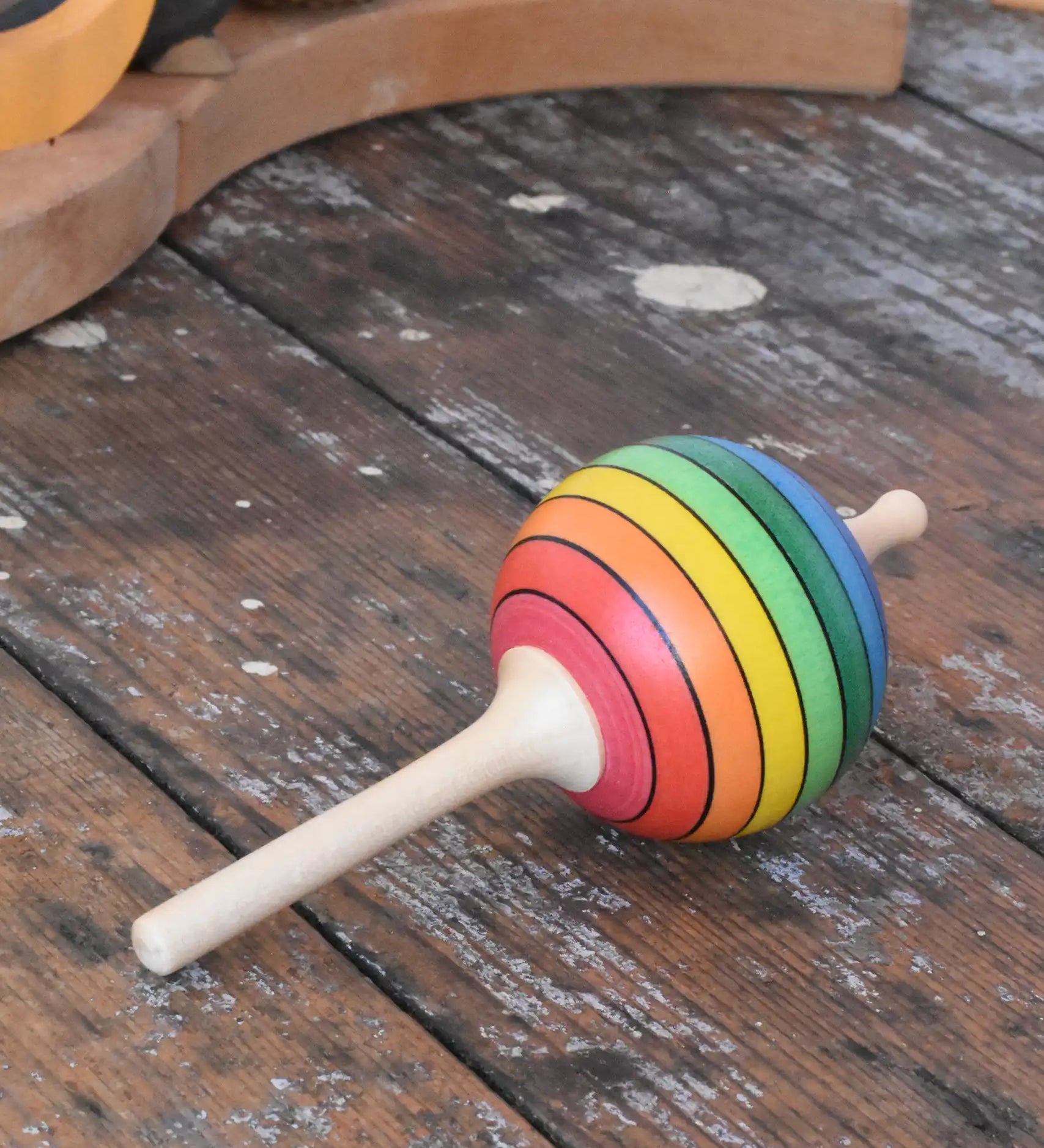 Mader Kreiselmanufaktur rainbow lolly spinning top placed on a wooden surface in the Babipur playroom.