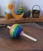 Mader Kreiselmanufaktur rainbow lolly spinning top placed on a walnut spinning plate in the Babipur playroom.