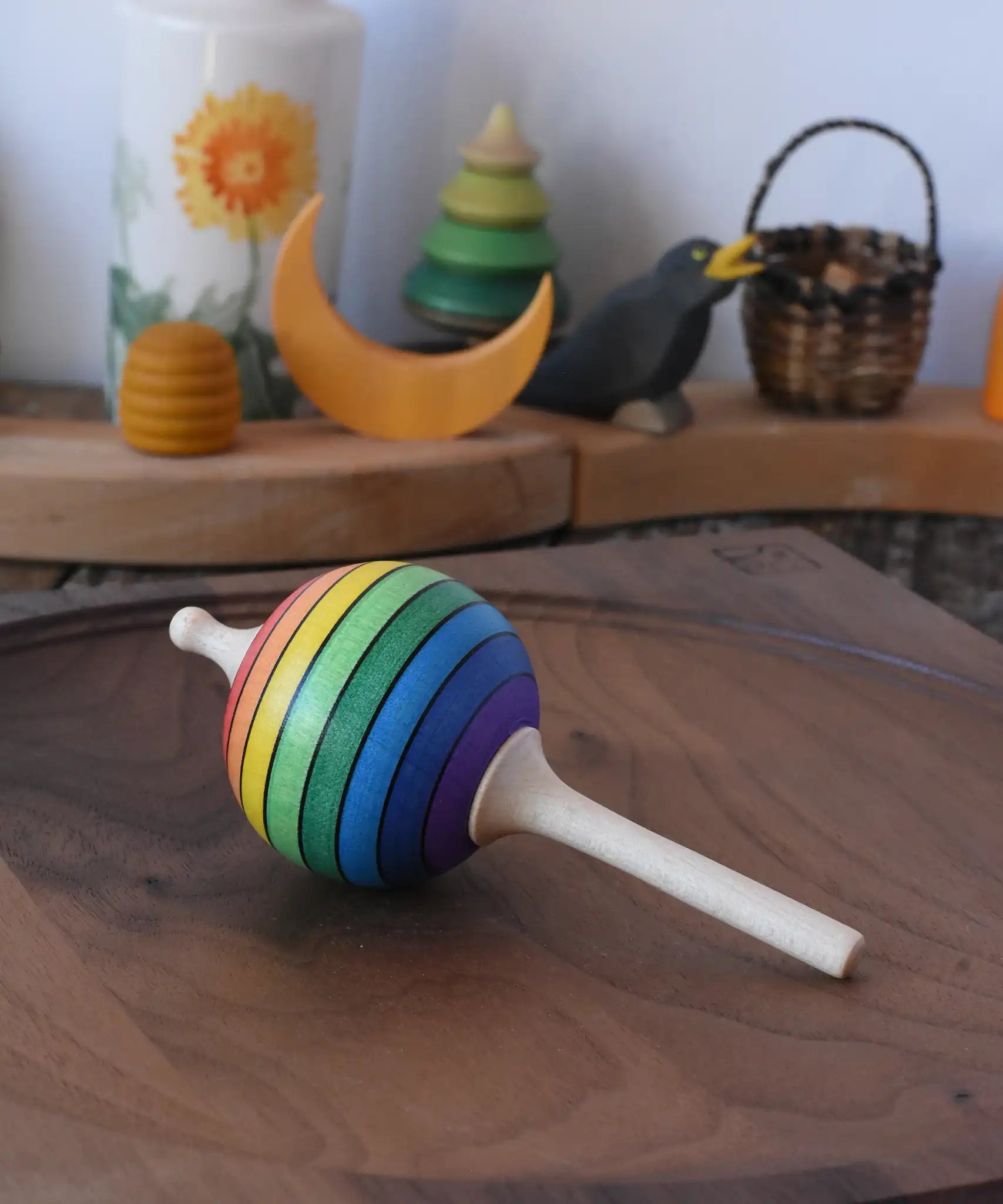 Mader Kreiselmanufaktur rainbow lolly spinning top placed on a walnut spinning plate in the Babipur playroom.