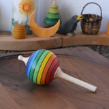 Mader Kreiselmanufaktur rainbow lolly spinning top placed on a walnut wood spinning plate in the Babipur playroom.