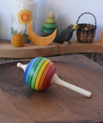 Mader Kreiselmanufaktur rainbow lolly spinning top placed on a walnut wood spinning plate in the Babipur playroom.