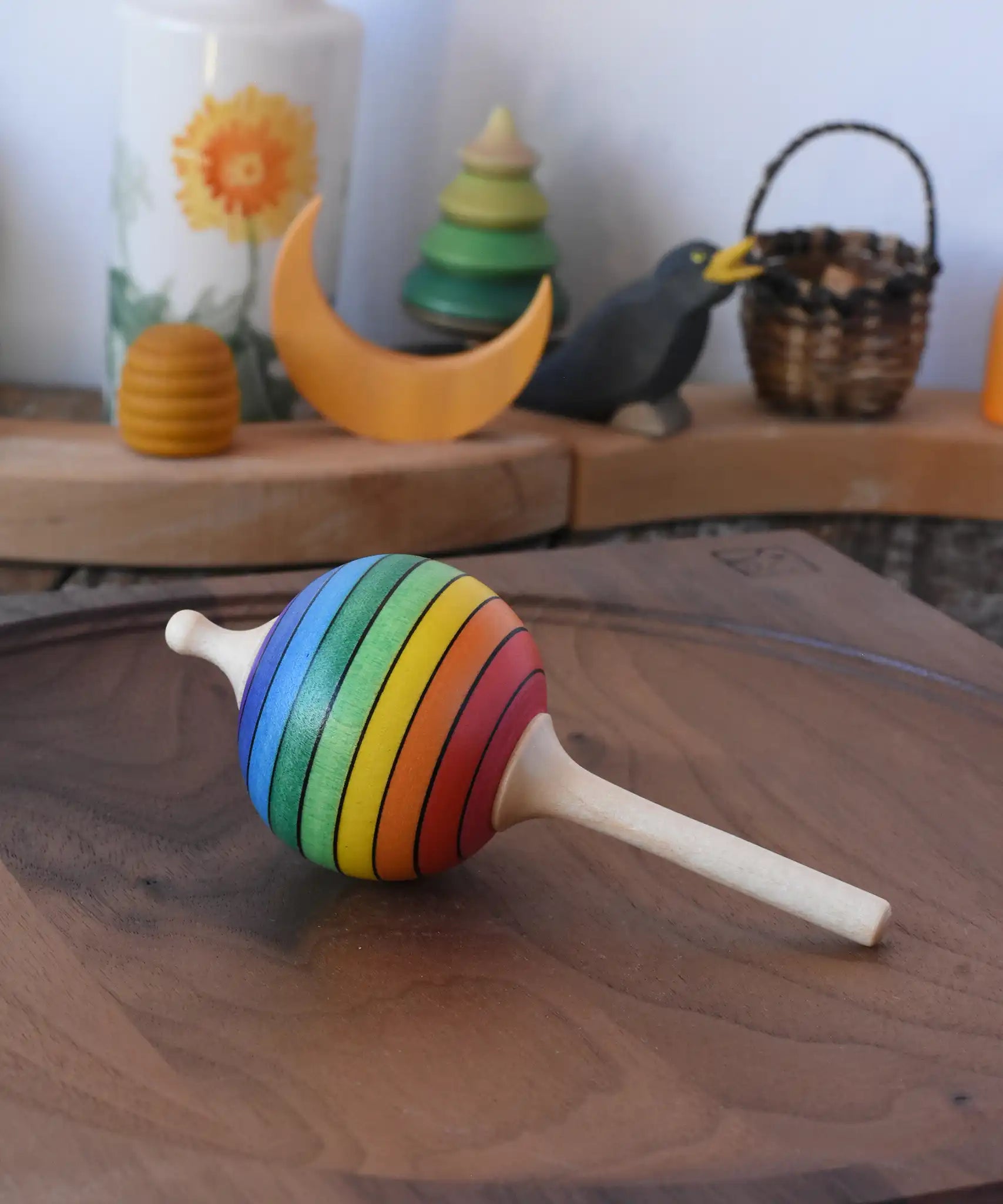 Mader Kreiselmanufaktur rainbow lolly spinning top placed on a walnut wood spinning plate in the Babipur playroom.