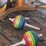 Two Mader Kreiselmanufaktur rainbow lolly spinning tops placed on a wooden surface in the Babipur playroom.