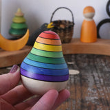 Mader wooden rainbow roly-poly wobbly pear toy in an adult's hand in the Babipur playroom.