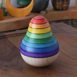 Mader wooden rainbow roly-poly wobbly pear toy placed on a walnut wood plate in the Babipur playroom.