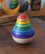 Mader wooden rainbow roly-poly wobbly pear toy placed on a walnut wood plate in the Babipur playroom.