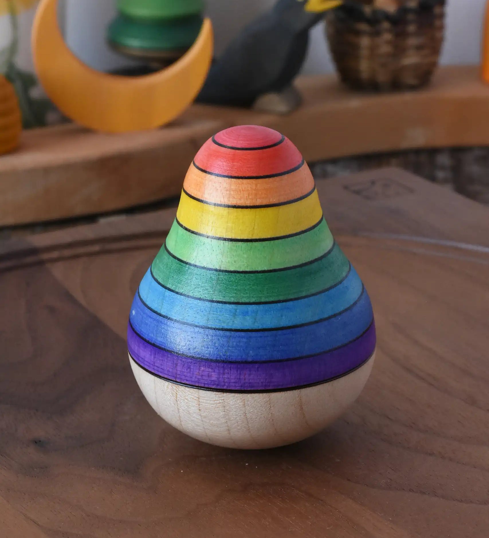 Mader wooden rainbow roly-poly wobbly pear toy placed on a walnut wood plate in the Babipur playroom.