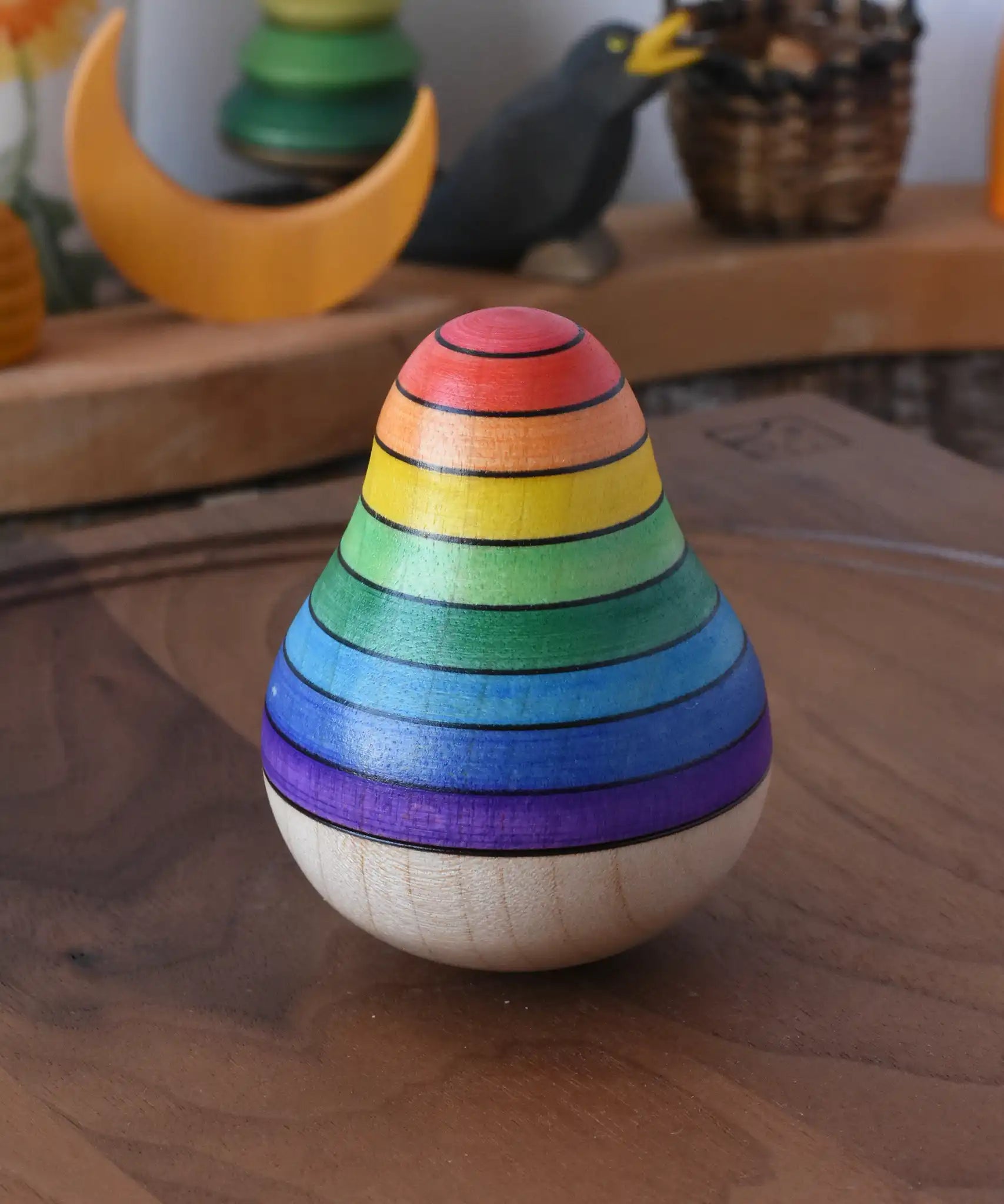 Mader wooden rainbow roly-poly wobbly pear toy placed on a walnut wood plate in the Babipur playroom.