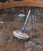 Mader Rainbow Spaghetti Spinning Top in blue placed on a desk in the Babipur playroom. 