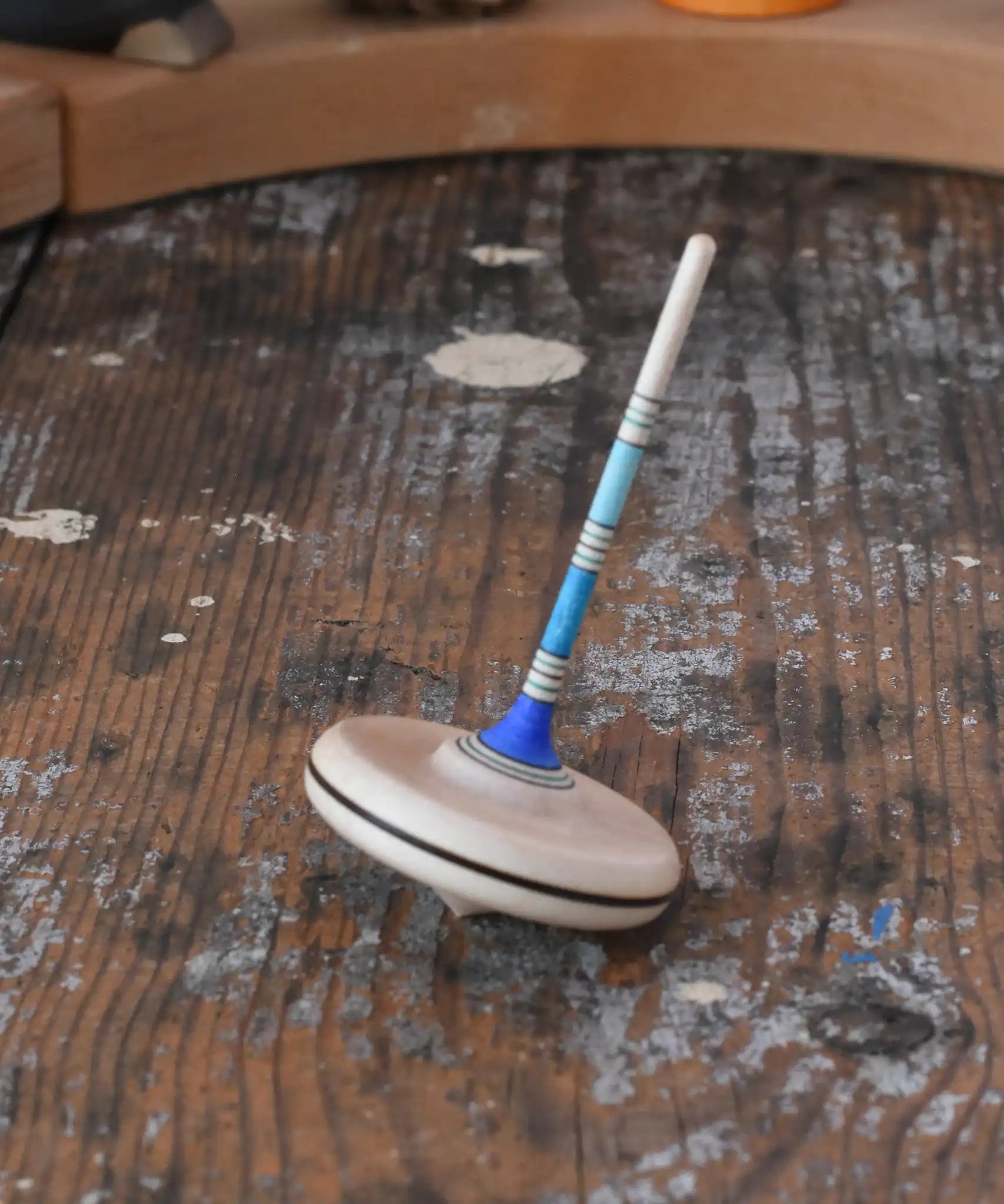 Mader Rainbow Spaghetti Spinning Top in blue placed on a desk in the Babipur playroom. 