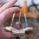 Mader Rainbow Spaghetti Spinning Top in an adult hand in the Babipur playroom. 