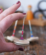 Mader Rainbow Spaghetti Spinning Top in an adult hand in the Babipur playroom. 
