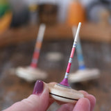 Mader Rainbow Spaghetti Spinning Top in an adult's hand in the Babipur playroom. 