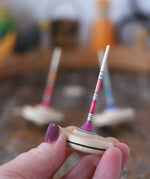 Mader Rainbow Spaghetti Spinning Top in an adult's hand in the Babipur playroom. 