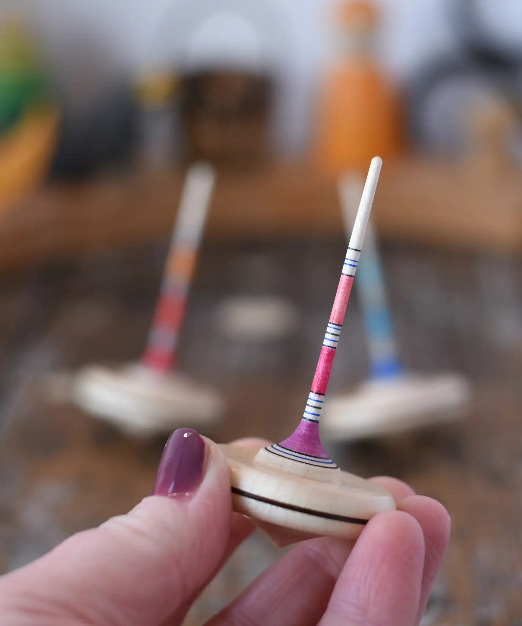 Mader Rainbow Spaghetti Spinning Top in an adult's hand in the Babipur playroom. 