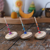 Three Mader Rainbow Spaghetti Spinning Tops in placed on a desk in the Babipur playroom. 