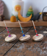 Three Mader Rainbow Spaghetti Spinning Tops in placed on a desk in the Babipur playroom. 