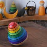 Mader wooden rainbow roly-poly wobbly pear toy wobbling on a walnut wood plate in the Babipur playroom.
