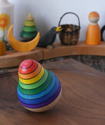 Mader wooden rainbow roly-poly wobbly pear toy wobbling on a walnut wood plate in the Babipur playroom.