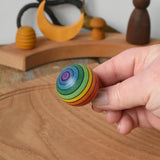 Mader Kreiselmanufaktur rainbow spinning turn-over top in an adult's hand in the Babipur playroom.