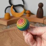 Mader Kreiselmanufaktur rainbow spinning turn-over top in an adult's hand in the Babipur playroom.