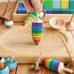 Close up of hand holding the Mader rainbow thunderbolt spinning top toy on a Mader spinning plate