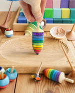 Close up of hand holding the Mader rainbow thunderbolt spinning top toy on a Mader spinning plate