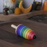 Mader rainbow stripe wooden spinning top placed on a walnut wood plate in the Babipur playroom. 