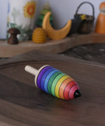 Mader rainbow stripe wooden spinning top placed on a walnut wood plate in the Babipur playroom. 