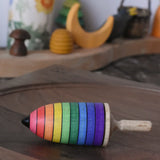 Mader rainbow stripe wooden spinning top placed on a walnut spinning plate in the Babipur playroom. 