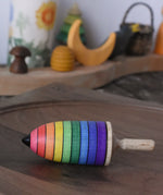 Mader rainbow stripe wooden spinning top placed on a walnut spinning plate in the Babipur playroom. 