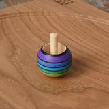 Mader Kreiselmanufaktur rainbow spinning turn-over top placed on an oak spinning plate on a wooden desk in the Babipur playroom.