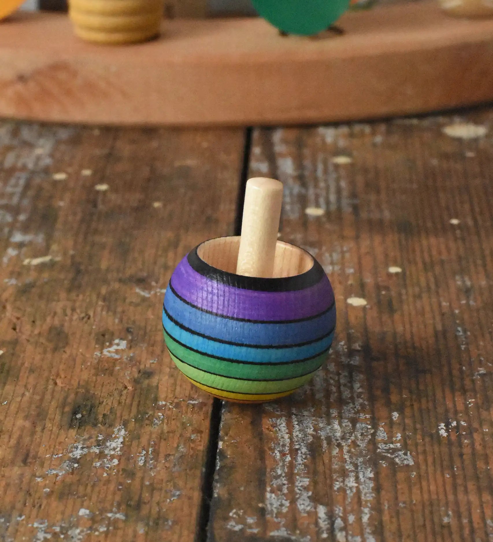Mader Kreiselmanufaktur rainbow spinning turn-over top placed on a wooden desk in the Babipur playroom.