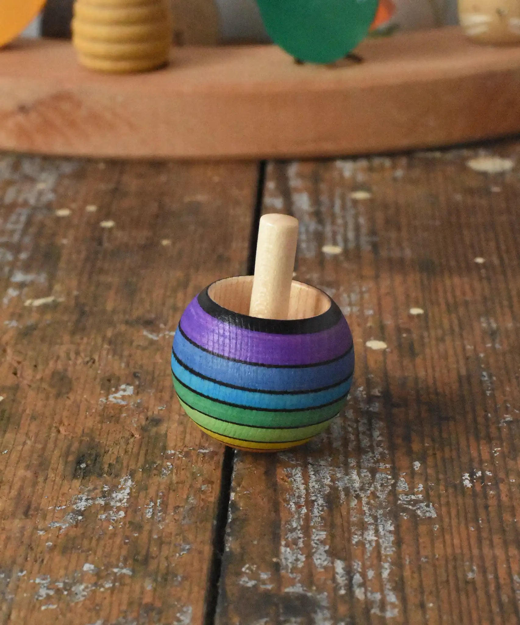 Mader Kreiselmanufaktur rainbow spinning turn-over top placed on a wooden desk in the Babipur playroom.