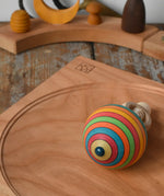 Bottom of the Mader Kreiselmanufaktur ring pull string spinning top placed on a cherry wood spinning plate in the Babipur playroom.