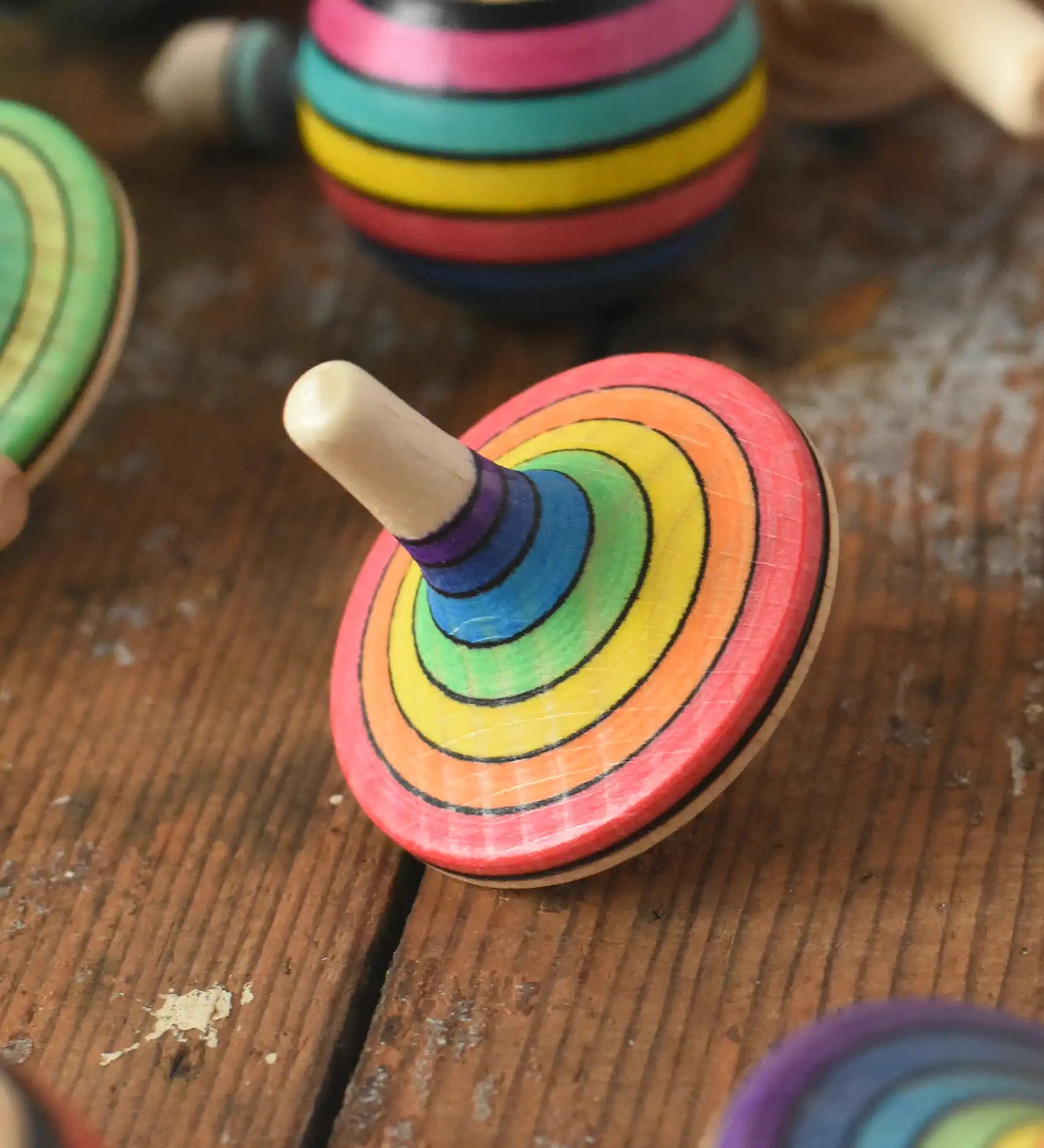 Mader Kreiselmanufaktur rainbow spinning top placed on a wooden surface in the Babipur playroom. 