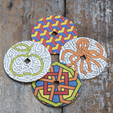 Mader patterned and coloured cardboard discs for 'So And So' Spinning Top placed on a wooden surface in the Babipur playroom. 