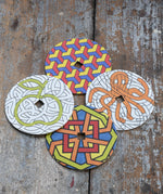 Mader patterned and coloured cardboard discs for 'So And So' Spinning Top placed on a wooden surface in the Babipur playroom. 