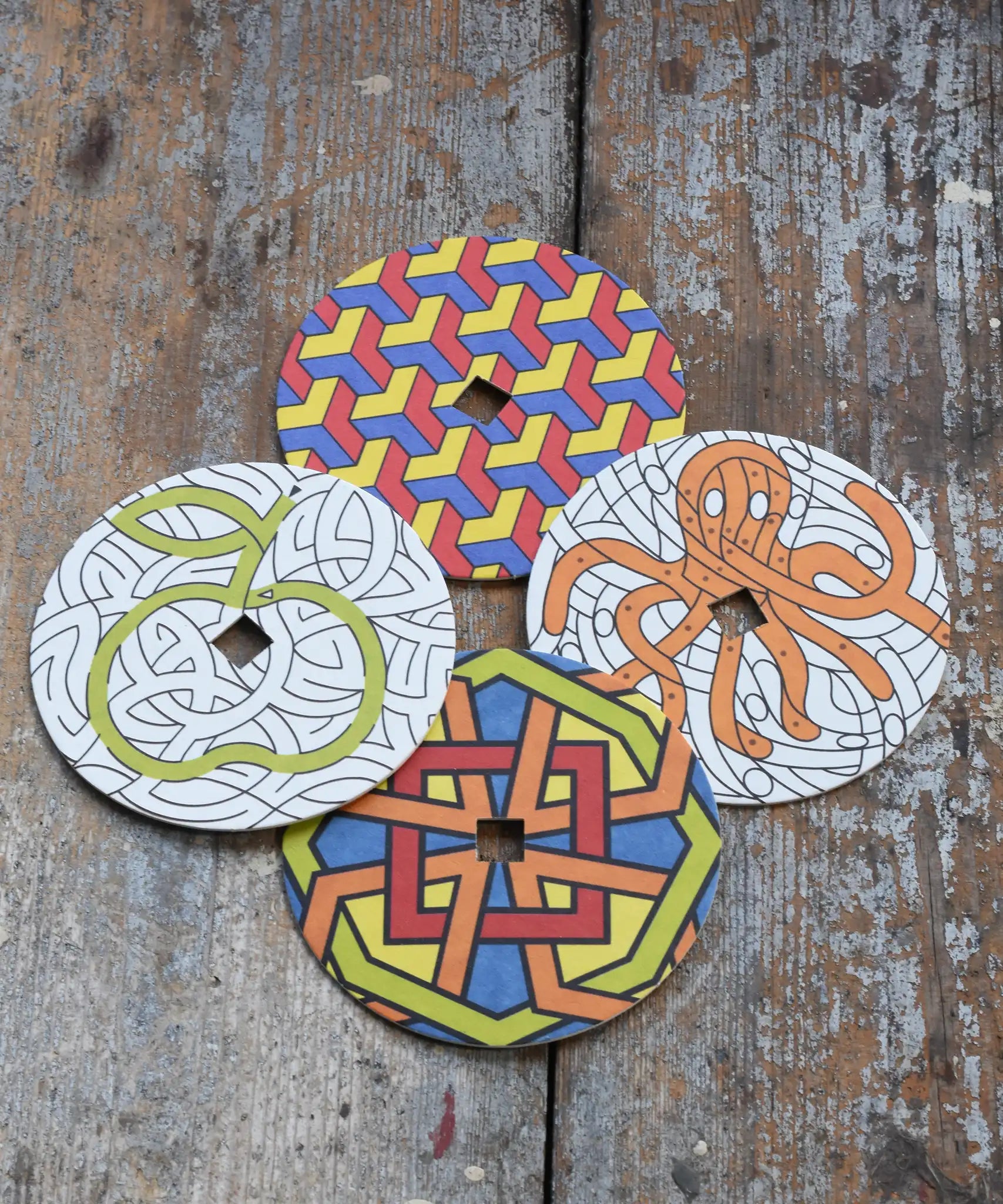 Mader patterned and coloured cardboard discs for 'So And So' Spinning Top placed on a wooden surface in the Babipur playroom. 